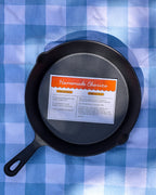 Overhead view of a cast iron skillet with the Homemade Chorizo recipe card inside, on a gingham cloth