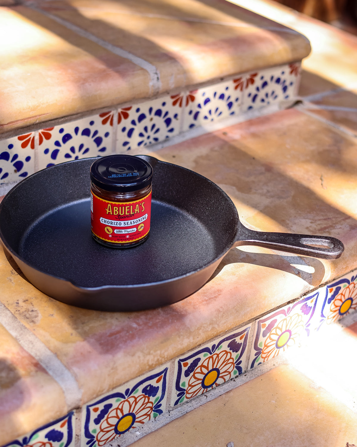 Spanish chorizo seasoning jar standing in a cast iron skillet on Talavera tile steps