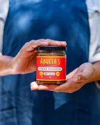 Hands cradling a jar of Spanish chorizo seasoning against the Blue linen apron