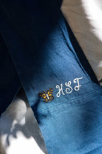 Close-up of the HSF monarch butterfly embroidery on the Blue linen apron strap