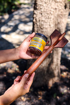 Two hands hold a five-blade teak chopper with a jar of Original chorizo seasoning