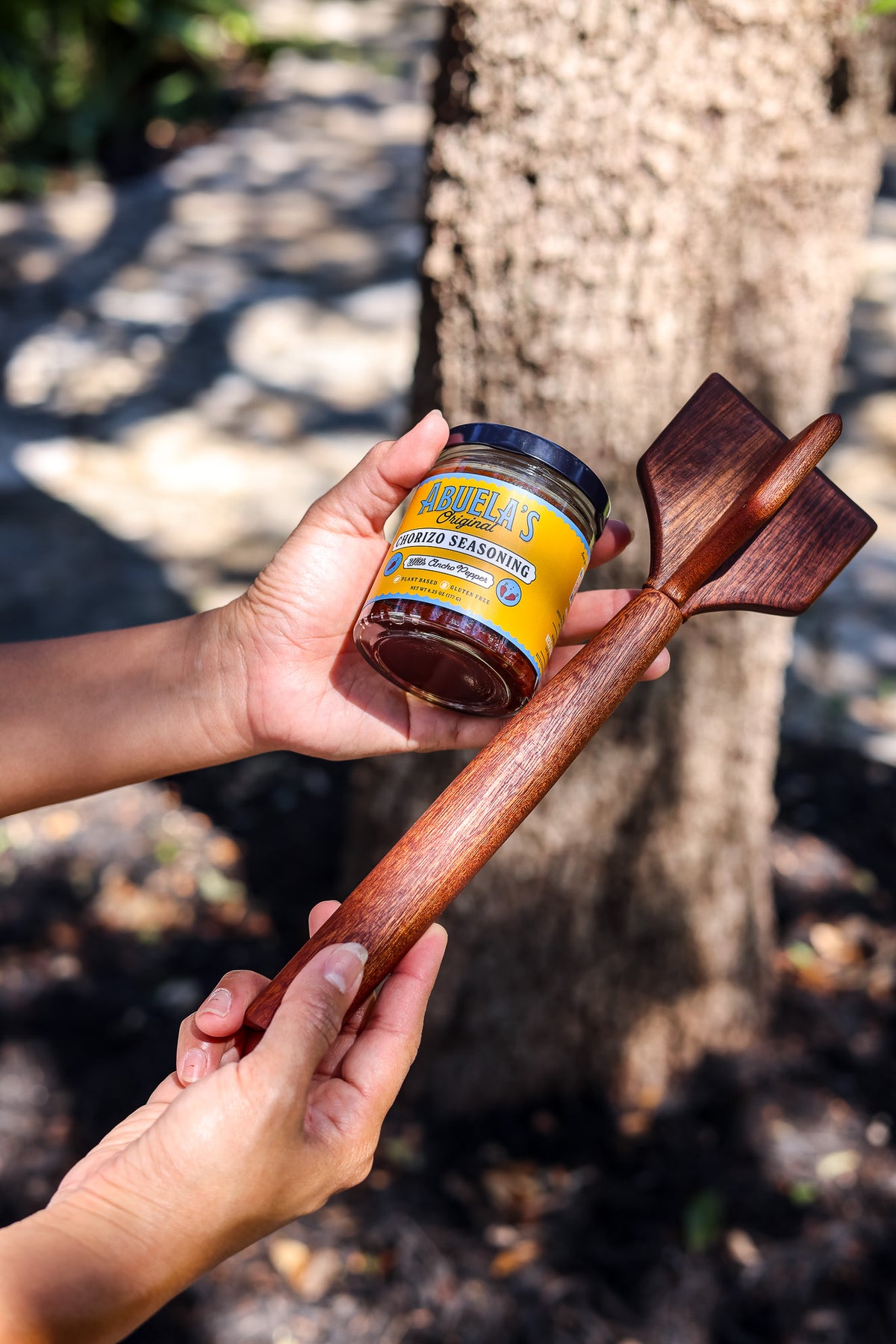 Two hands hold a five-blade teak chopper with a jar of Original chorizo seasoning