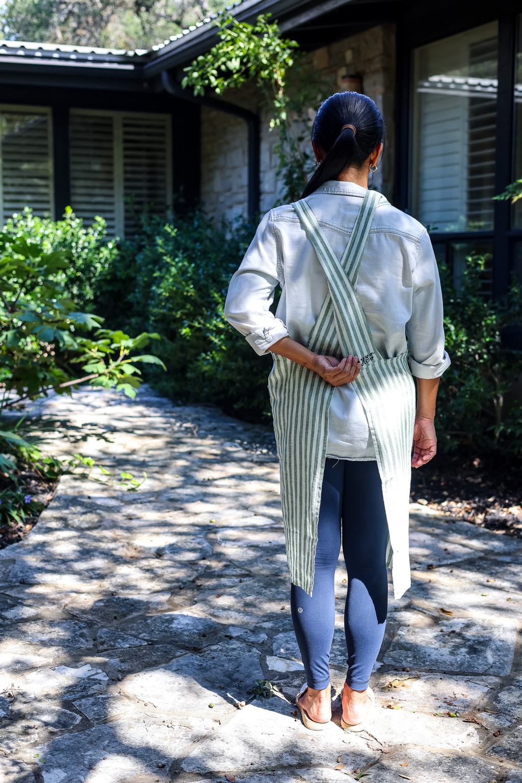 Back view of the Green Stripe cross-back linen apron on a garden path