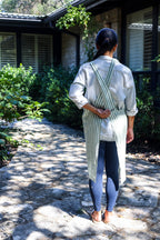 Back view of the Green Stripe cross-back linen apron on a garden path