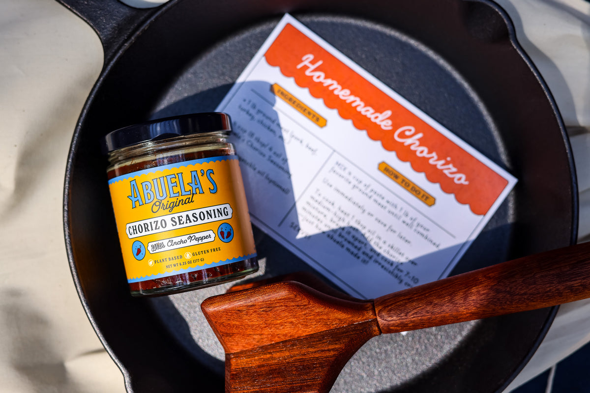 Original chorizo seasoning jar on the Homemade Chorizo recipe card inside a cast iron skillet with teak chopper
