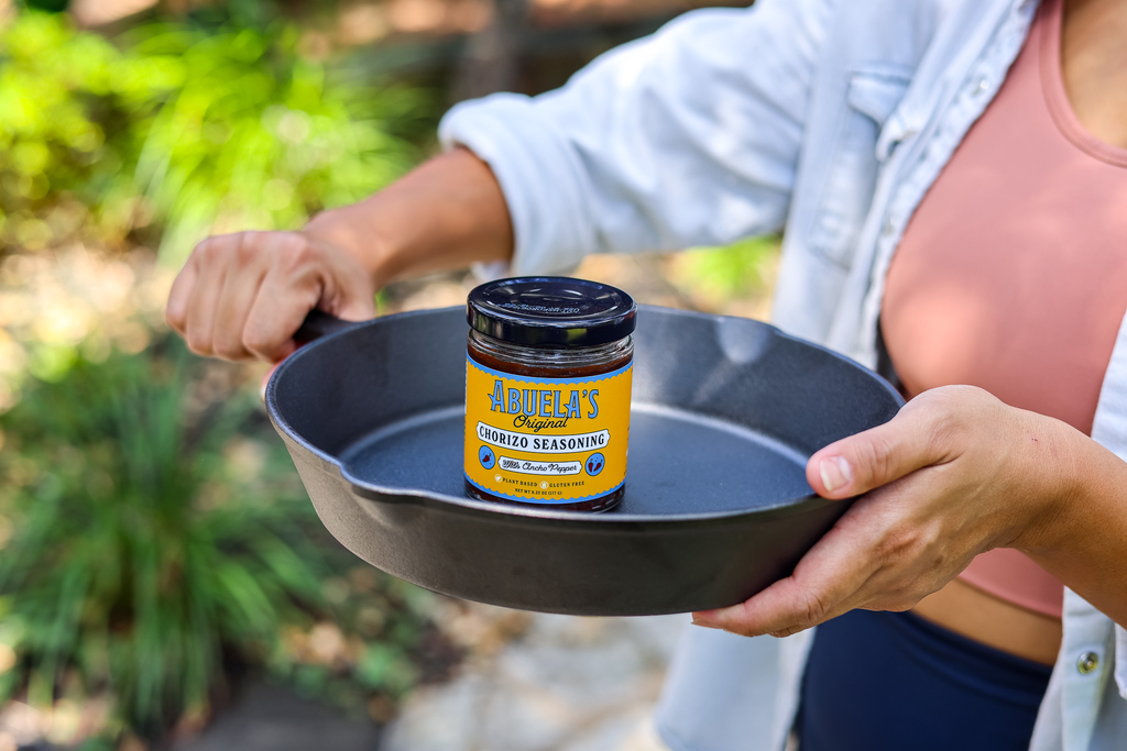 Close view of hands holding a cast iron skillet with Original chorizo seasoning in the center