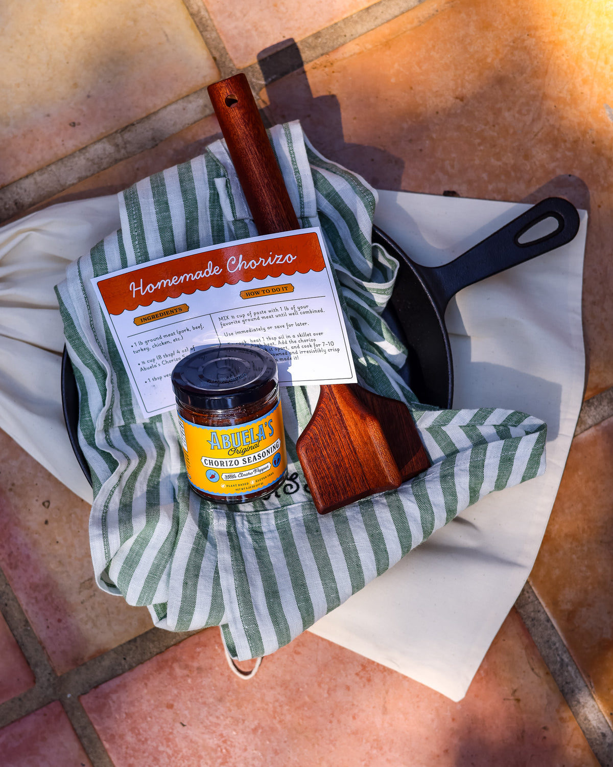 Chorizo kit gift bundle with the Green Stripe apron tucked in the skillet, Original seasoning jar and teak chopper