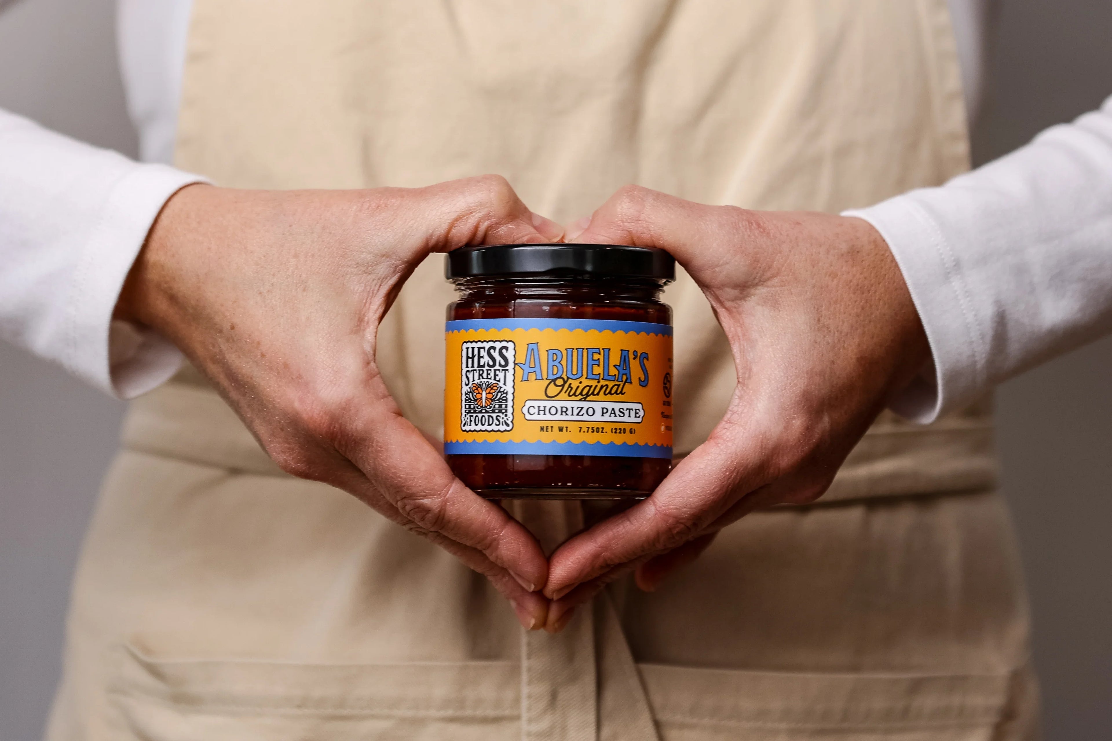 Person holding a jar of 'Abuela's' food product with a neutral background