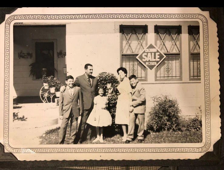 Vintage black and white photo of a family in front of a house with a 'For Sale' sign.