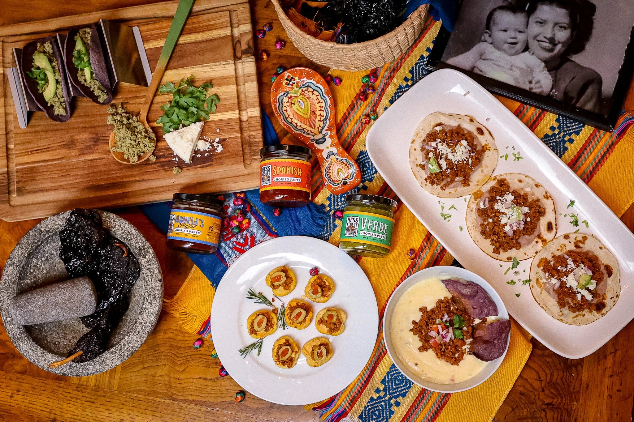 Diverse food items including tortillas, salsas, and a baby photo on a colorful tablecloth.